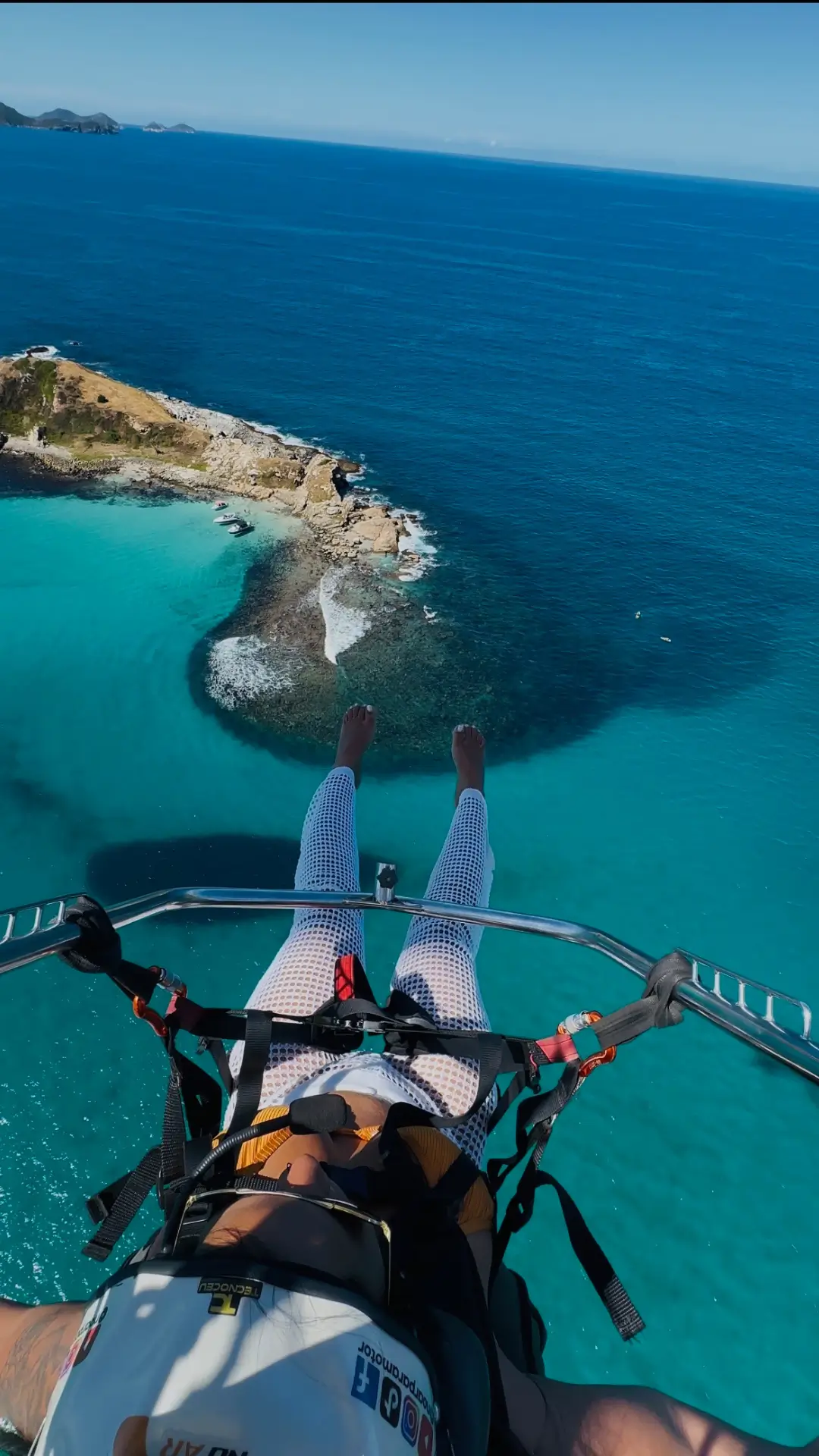 Aluno de paramotor acenando com a paisagem do mar ao fundo